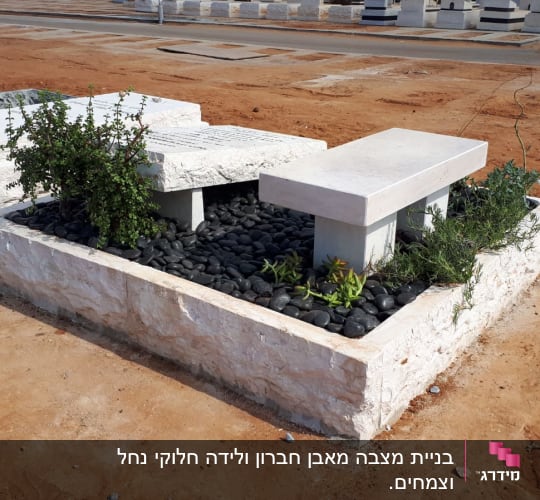 קבר עם מצבה, אבנים שחורות וצמחייה ירוקה